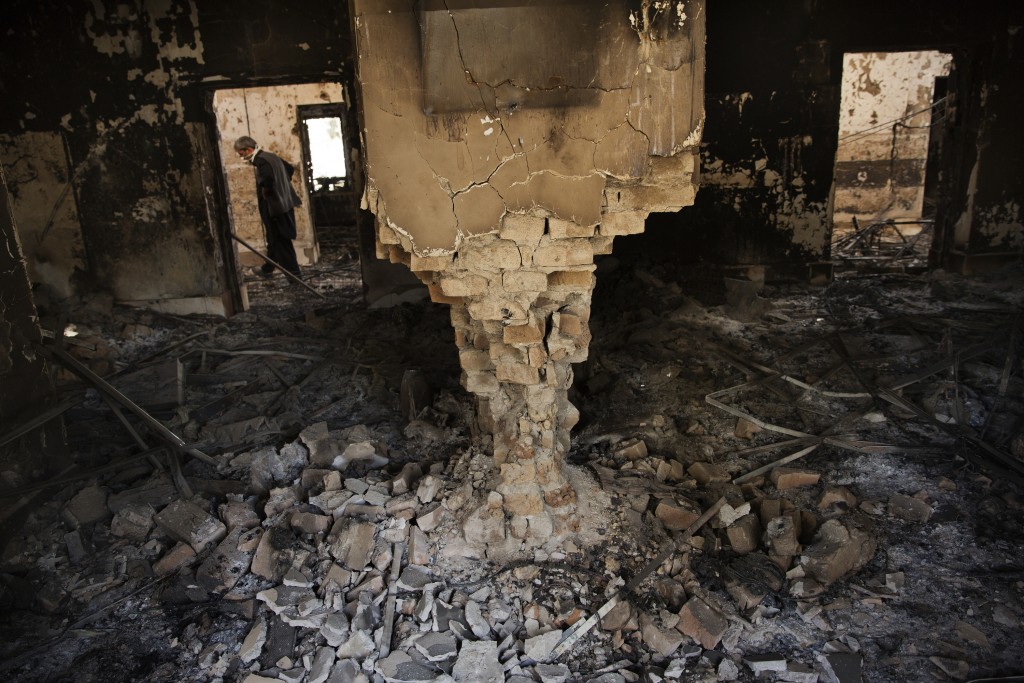 A man wearing a surgical mask walks, 14 October 2015, amongst the debris of the damaged and burnt-out MSF Trauma Centre in Kunduz, northern Afghanistan.